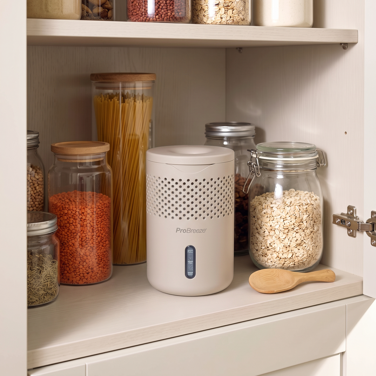 A light sage green Pro Breeze moisture absorber sits on a kitchen shelf next to glass jars filled with pasta, lentils, and oats.