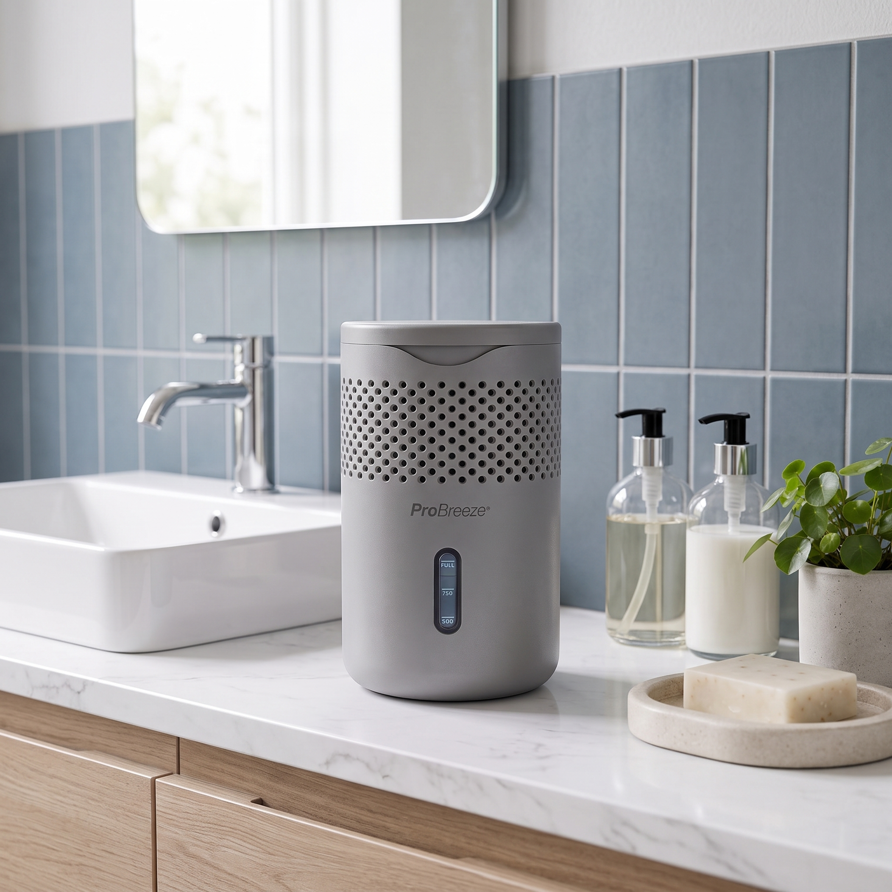 A gray Pro Breeze moisture absorber sits on a white marble bathroom counter next to a sink, soap dish, and toiletries, with a blue tiled wall in the background.